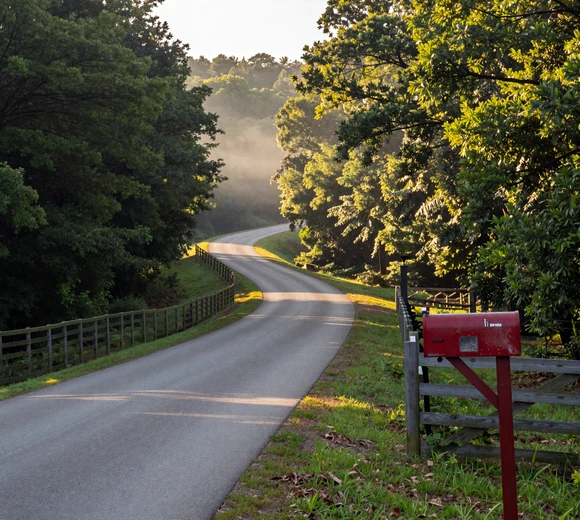 Winding country road through Ozark Mountains with morning mist and split-rail fence - rural dating Arkansas