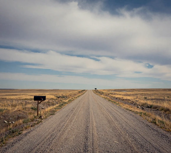 Long empty gravel road through vast Montana prairie showing extreme rural isolation - rural singles Billings